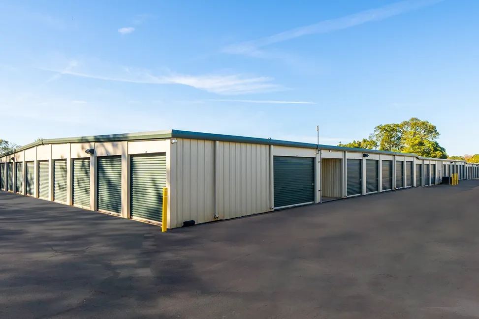 Drive-up storage units with green roll-up doors and wide paved access lanes